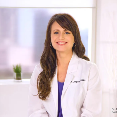 Meet Medical Advisor HairClub Dr. Phipps - Dr. Angela Phipps wears a white lab jacket and is sitting, ready to answer hair loss questions.