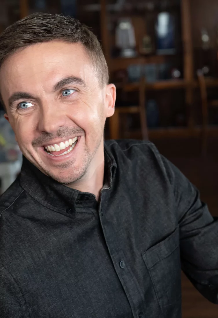 Celebrity Frankie Muniz - wearing a black dress shirt and smiling with nicely styled hair.