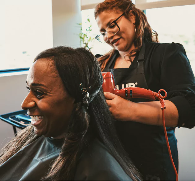 HairClub - Hair You Will Love - a Hairclub Hair Loss Specialist professionally styling a woman's long black hair at a HairClub Center.