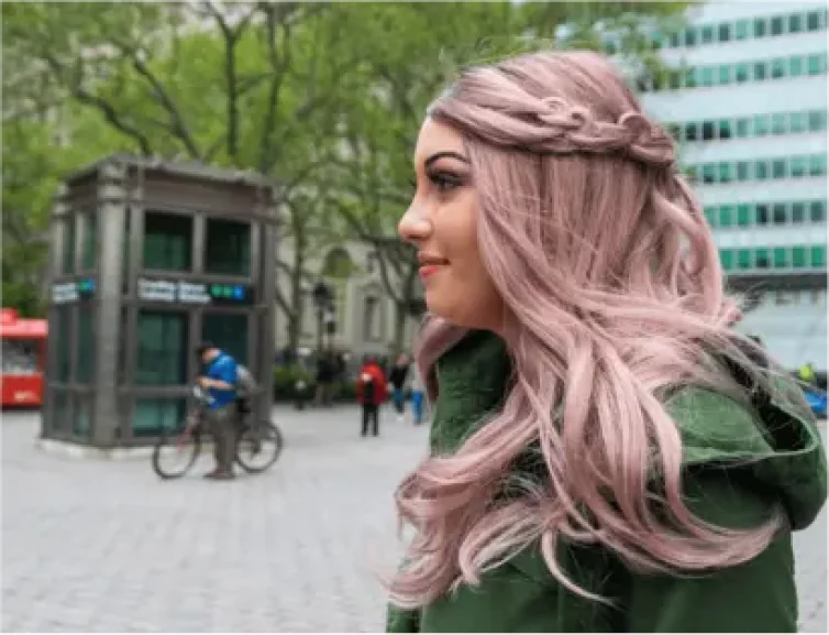 Results - a woman outside in a city walking to the left - she has long, voluminous, pink-tinted hair that falls over her shoulders.